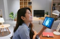Image of woman marveling over a smart home tablet she is holding