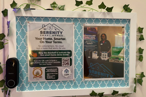 Close-up of Serenity Smart Homes branded bulletin board with logo, tagline, CLIPP certification seal, Top Smart Home Provider badge, QR code, and Reolink doorbell camera integrated into the frame with trailing ivy decoration