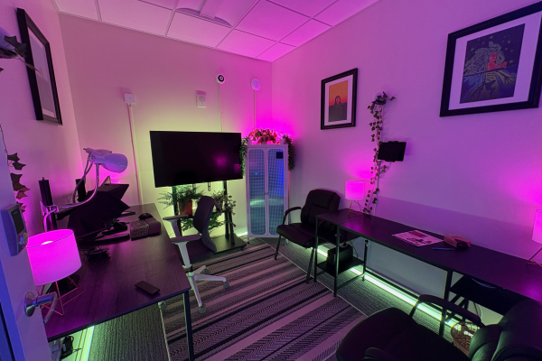 Showroom in green lighting scene with teal floor perimeter strips, Hue table lamps glowing warm pink, cabinet glowing blue through gingham doors, and artwork visible on walls