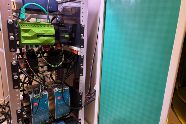 Hand-built mini rack interior showing Loxone Miniserver Compact and Stereo Extension on custom DIN rails, two Mean Well NDR-240-24 transformers, Wago terminal block wiring, teal ethernet cable to Beelink mini PC