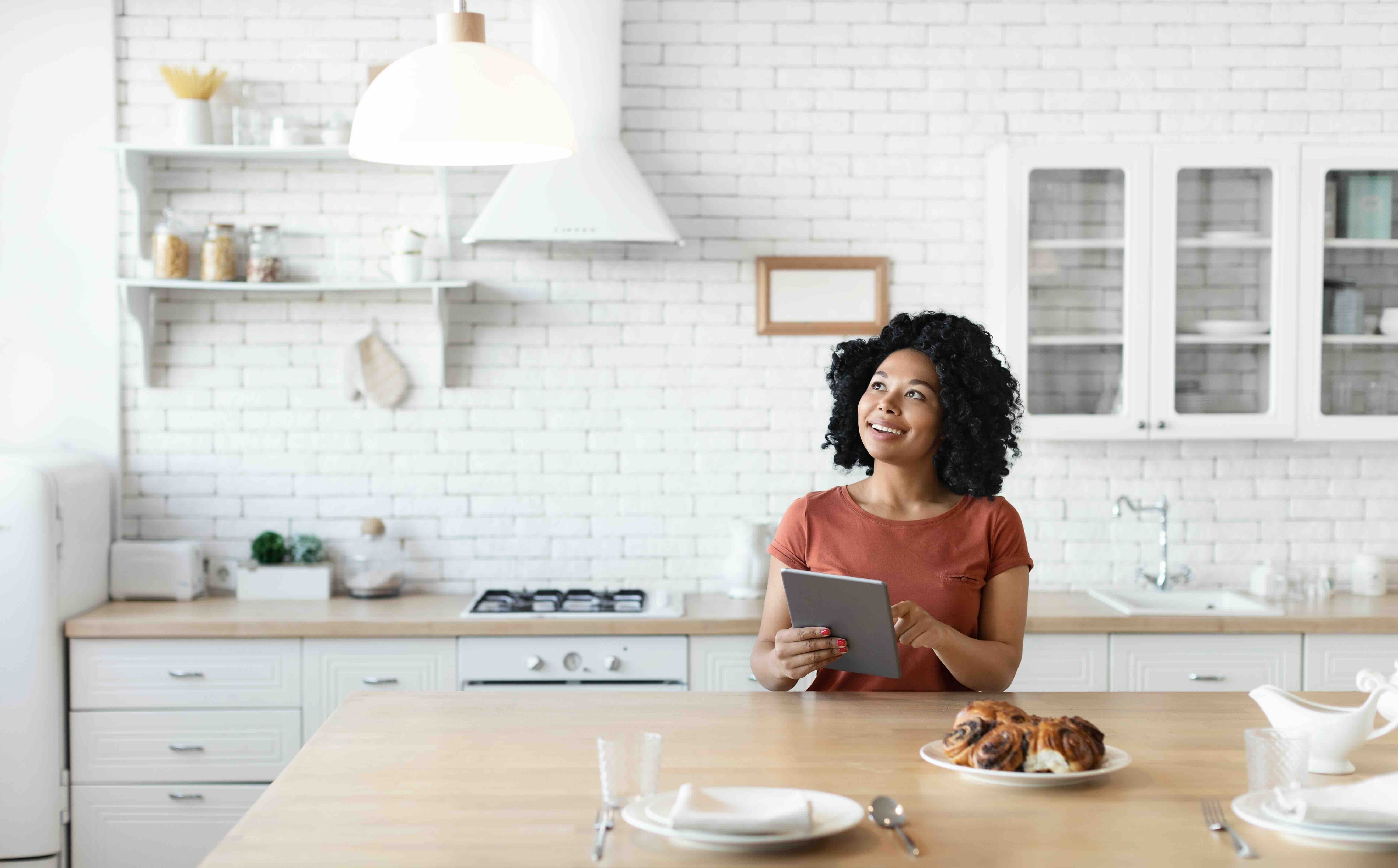 Black woman handling tablet in light colored kitchen