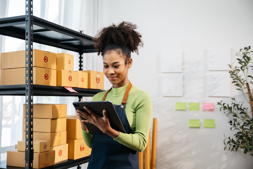 Image of woman looking at a clipboard while standing next to shelves with lots of boxes